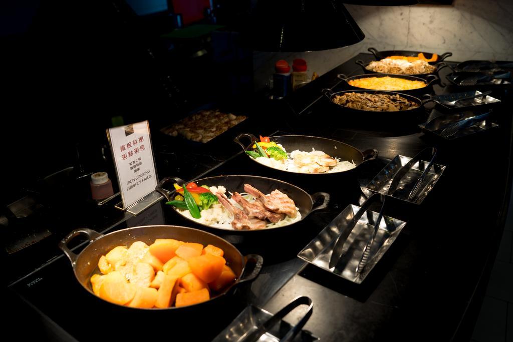 Ambassador Hotel Гаосюн Экстерьер фото The photo shows a buffet-style food display featuring several dishes in oval serving pots. There are a variety of cooked vegetables and meats, with one pot containing a mix of root vegetables or squash, another with meat and vegetables, and possibly 
